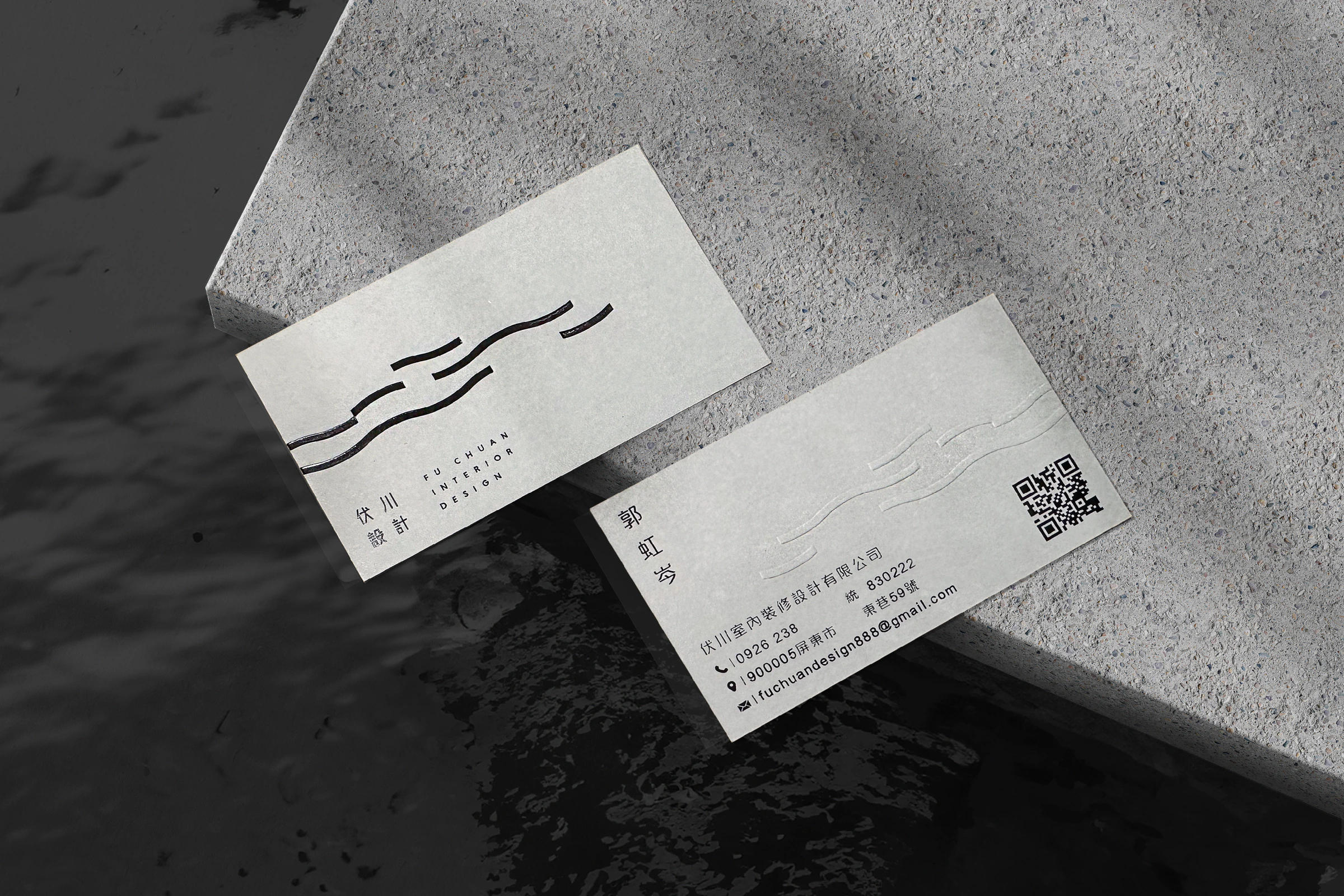 伏川設計兩張灰白名片置於水面旁的混凝土台面，呈現水流標誌及聯絡資訊