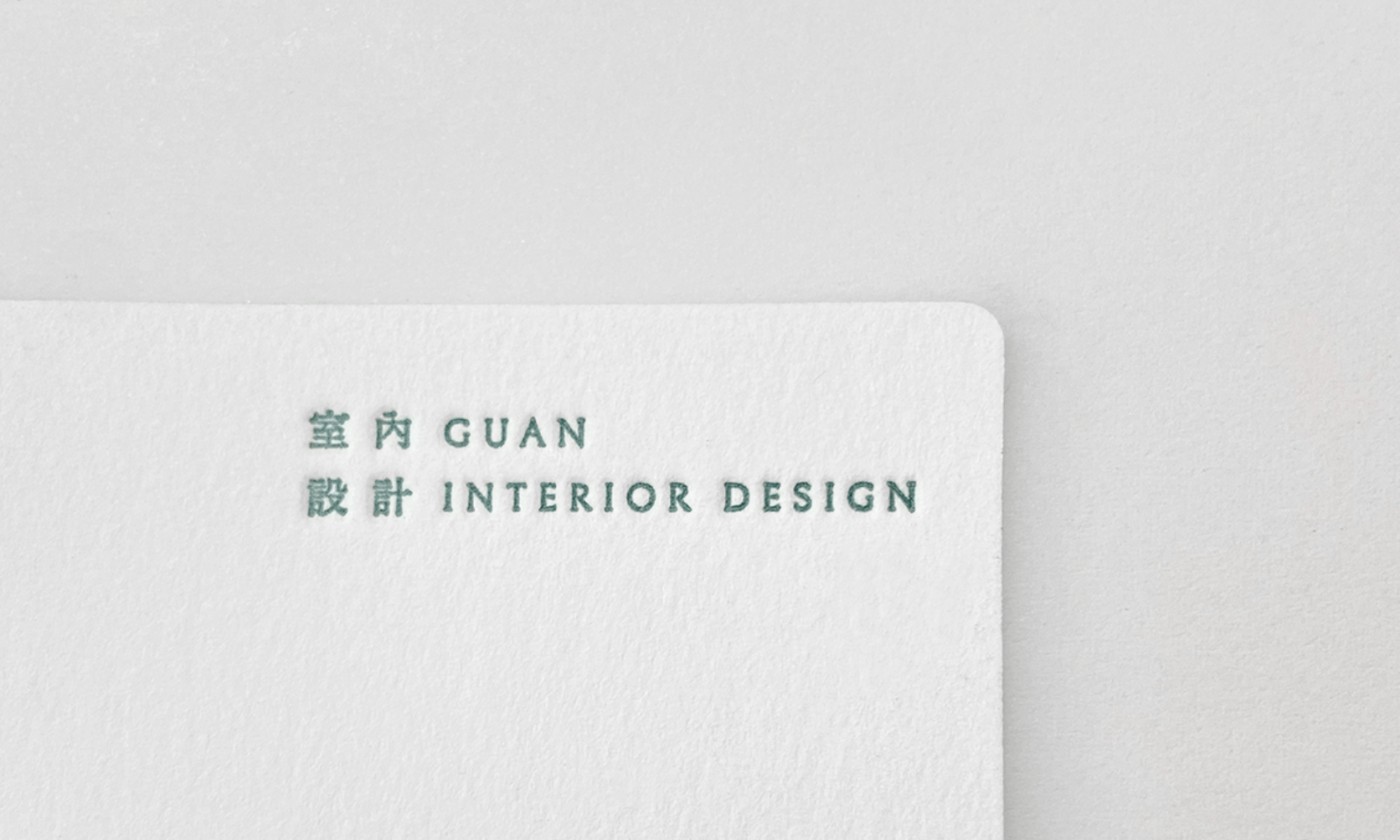 觀室內設計米白名片局部近拍，呈現綠色 GUAN INTERIOR DESIGN 字樣